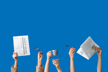 Female hands holding newspapers with eyeglasses, cup of coffee and smoking pipe on blue background