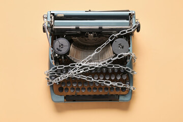 Vintage typewriter with chains on beige background. Printing ban concept