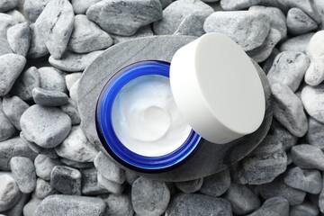Jar of moisturizing cream on stones, top view