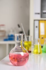 Laboratory analysis. Flask with pink liquid on white table