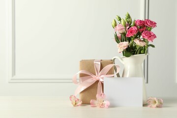 Happy Mother's Day. Gift box, blank card and beautiful flowers on white table. Space for text