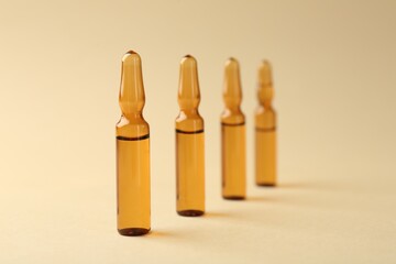 Glass ampoules with liquid on beige background