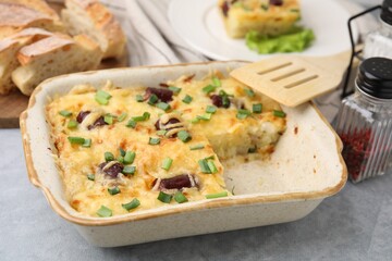 Tasty sausage casserole with green onions served on grey table, closeup
