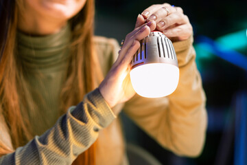 Young influencer filming review of light bulb able to change into different colors, close up shot. Content creator showcasing smart home automation technology in apartment studio