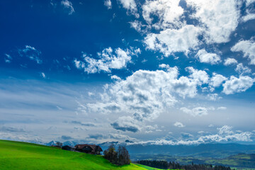 Eindrücklicher Wolkenhimmel mit grüner Landschaft - obrazy, fototapety, plakaty