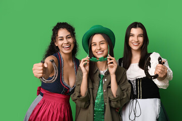 Beautiful young women with horseshoes on green background. St. Patrick's Day celebration