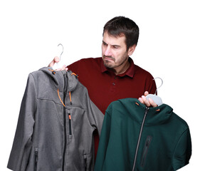 A dark-haired man of 40-45 years old holds a hanger in his hands, the concept of buying and choosing clothes