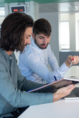 Obraz premium Travail en équipe. deux collègues travaillent ensemble dans un bureau sur le même projet. Ils discutent et sont assis devant un ordinateur portable.