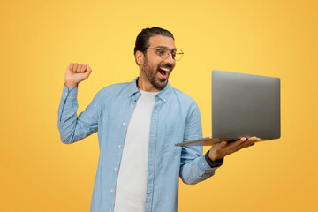 Happy man celebrating with laptop
