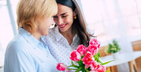 Banner image of happy daughter and mom with tulips bouquet. Birthday, Mothers day, women's day, retired, family, relation, motherhood. - 773486033