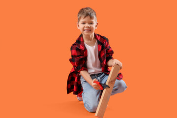 Cute little builder sawing wooden plank on orange background - obrazy, fototapety, plakaty