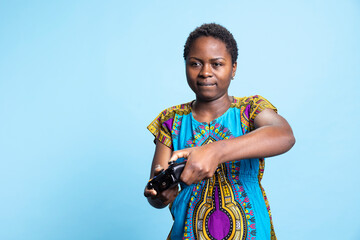 African american woman enjoying gaming challenge in studio, playing videogames with a controller. Smiling young adult having fun with online gaming championship, participates in cyber sport.