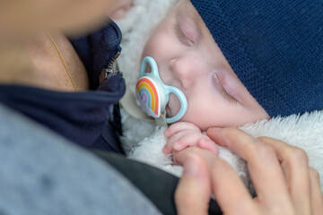Extreme close up of little baby sleeping with a pacifier and holding mothers hand