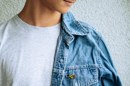 Teenage boy with autism infinity rainbow symbol sign metallic pin brooch on denim jacket. World autism awareness day, autism rights movement, neurodiversity, autistic acceptance movement