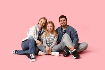 Happy family in stylish denim clothes sitting on pink background