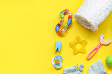 Children's toothbrush with towel, pacifier and toys on yellow background