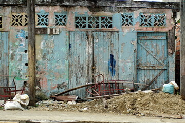 Trash in front of a building with blue, peeling paint in Limones, Esmereldas, Ecuador
