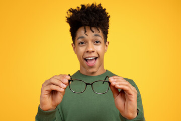 Excited young black man holding glasses