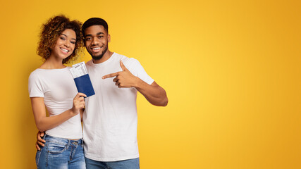 Happy young black couple holding passports and tickets