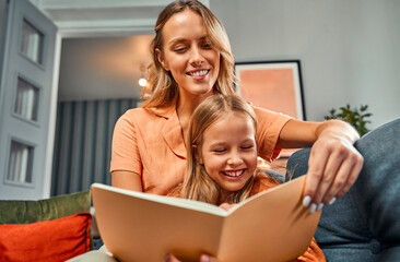 Excitement from learning. Young mother enjoying reading book together with child while doing homework