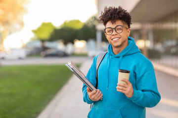 Smiling student holding coffee and binders