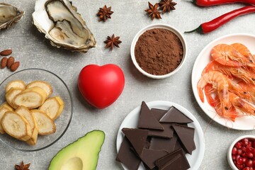 Natural aphrodisiac. Different food products and heart model on grey table, flat lay