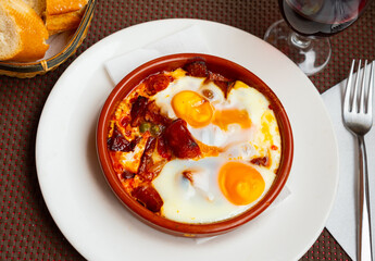Huevos con chistorra - fried eggs with sausages served with potatoes - obrazy, fototapety, plakaty