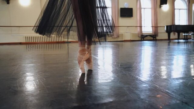 Close-up of the legs of a ballerina in pointe shoes dancing on the floor