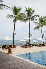 Beach beds with umbrellas, on the ocean coastline, on the hotel grounds among greenery.