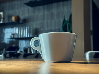 White cup of coffee on the table. Background of a blurred bar.