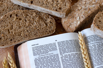 Whole grain bread and wheat with open holy bible book on wood. Top table view. Eating spiritual...