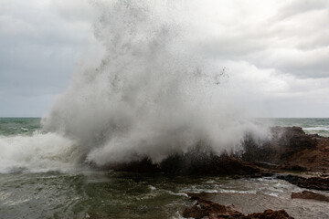 Sea waves crashing hard against a rock in winter.