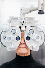 Elderly patient looking through phoropter in an ophthalmology clinic. Vision or eyesight care concept