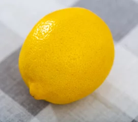 Schilderijen op glas There is whole yellow lemon on wooden table. Lemon peel texture close-up, isolated © JackF
