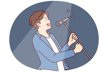Man pop star sings song leaning back with microphone on tripod in hands during performance at concert. Happy guy performs popular song for own fans while standing in spotlight