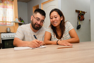 Happy young married couple sitting at home calculating household expenses. couple doing their...