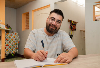 Hispanic man doing bills and reviewing his home finances - adult man doing home school - adult...