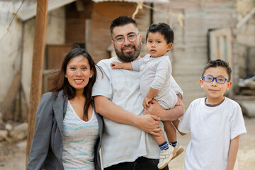 Portrait of happy Hispanic family outside his house in a rural area. Latin family smiling at the...