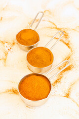 Natural cinnamon powder in metal bowls on white surface
