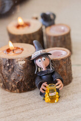 Fototapeta premium Witch figurine with bottle of potion and candle on the table