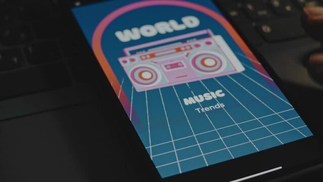 World music trends inscription on blue background. Graphic presentation with vintage cassette recorder drawing on smartphone screen. Male hands flapping fingers cheerfully. VHS effect