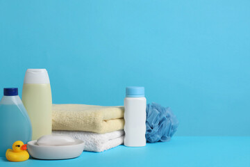 Obraz na płótnie Canvas Baby cosmetic products, bath duck, sponge and towels on light blue background. Space for text