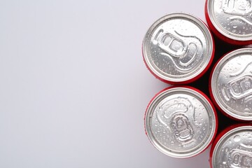 Energy drinks in wet cans on light grey background, top view. Space for text