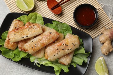 Tasty fried spring rolls served on gray table, flat lay