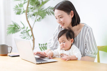 赤ちゃんと一緒にパソコンを使うママ
