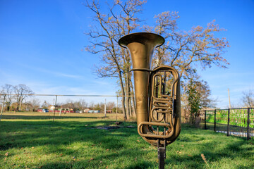 A brass instrument is sitting in a grassy field