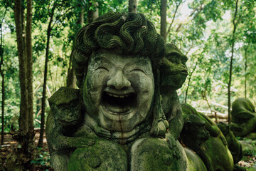 Fototapeta na wymiar Stone sculpture of happy face and monkeys in Monkey Forest. Ubud, Bali, Indonesia.