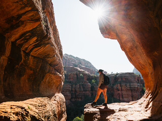 Secret Subway Cave Boynton Canyon Sedona solo female hiker staring off into cliff with sunstar.