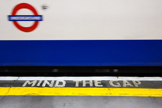 London, UK - March 24, 2024; Mind The Gap warning on platform with blurred passing London Underground tube train