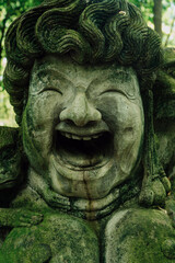 Fototapeta na wymiar Stone sculpture of happy face and monkeys in Monkey Forest. Ubud, Bali, Indonesia.